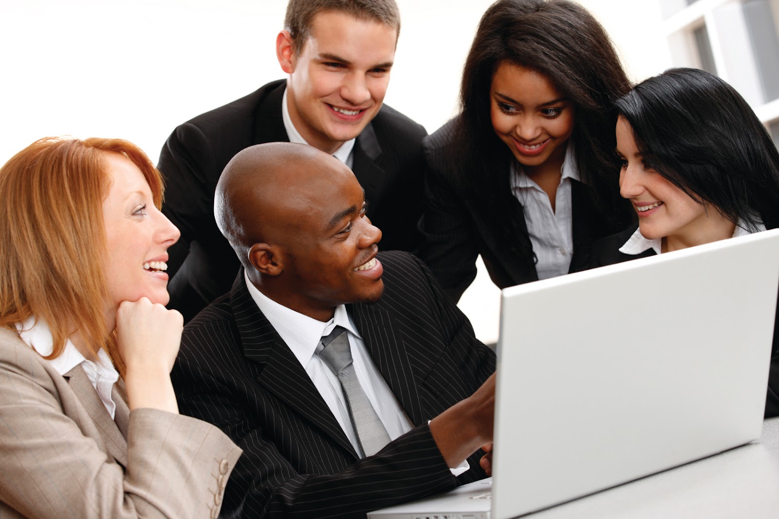 A group of people sitting around a laptop